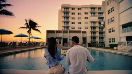Two young people sitting by the pool during sunset.