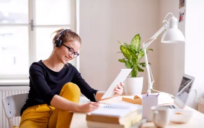 Woman on tablet working with headphones.