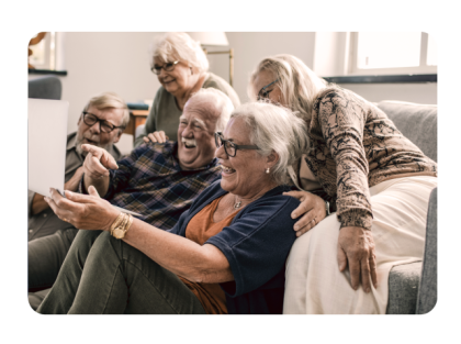 Group of senior citizens smiling and looking at a laptop