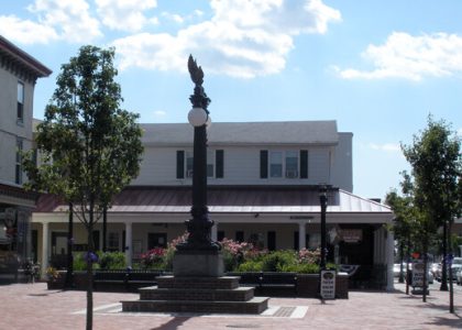 A town square in Delaware with a monument and general store in view.