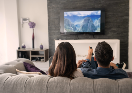 Man and woman sitting on a couch watching TV