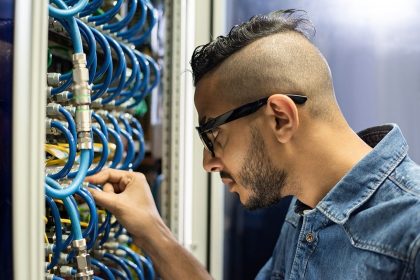 Two men are reviewing diagnostics on a laptop in a commercial server room.