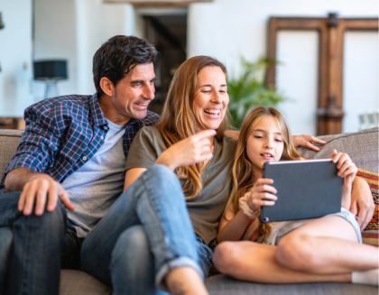 Family sitting on couch sharing tablet