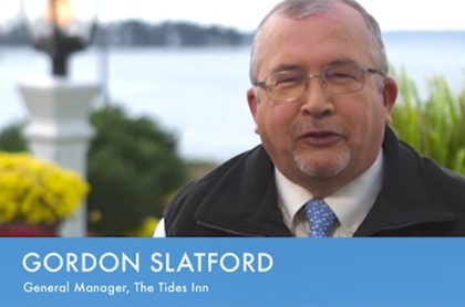 Gordon Slatford, General Manager of Titles Inn being interviewed outside with a trees and a body of water in the distance in the background.