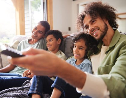 Family sitting on couch watching TV together