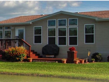 The side of a single Cypress Lakes unit with green grass and partly cloudy blue sky.