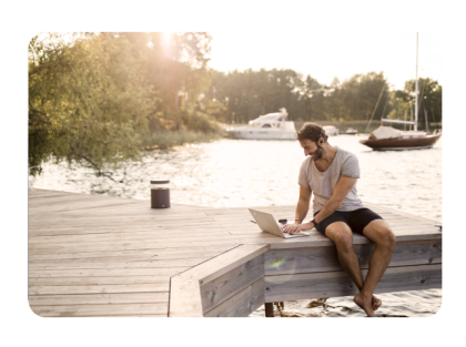 Man sitting on a dock with a laptop by lake