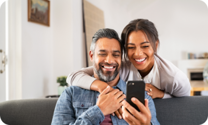 Man and woman smiling looking at a mobile phone