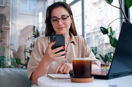 Young woman holding mobile phone at a cafe