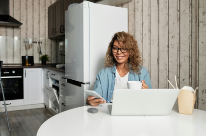 Woman sitting in kitchen smiling and looking at mobile phone