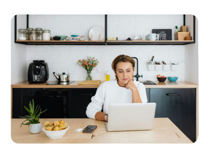 Woman in kitchen looking at laptop