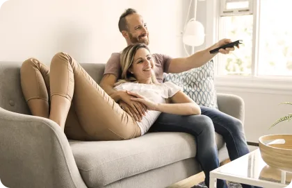 A couple watching TV together on a couch.