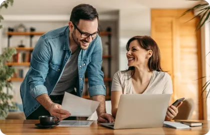 Man and woman smiling while looking at a laptop