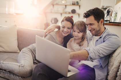 Family looking at a laptop while sitting on a couch
