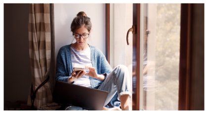 Woman looking at her phone with a laptop